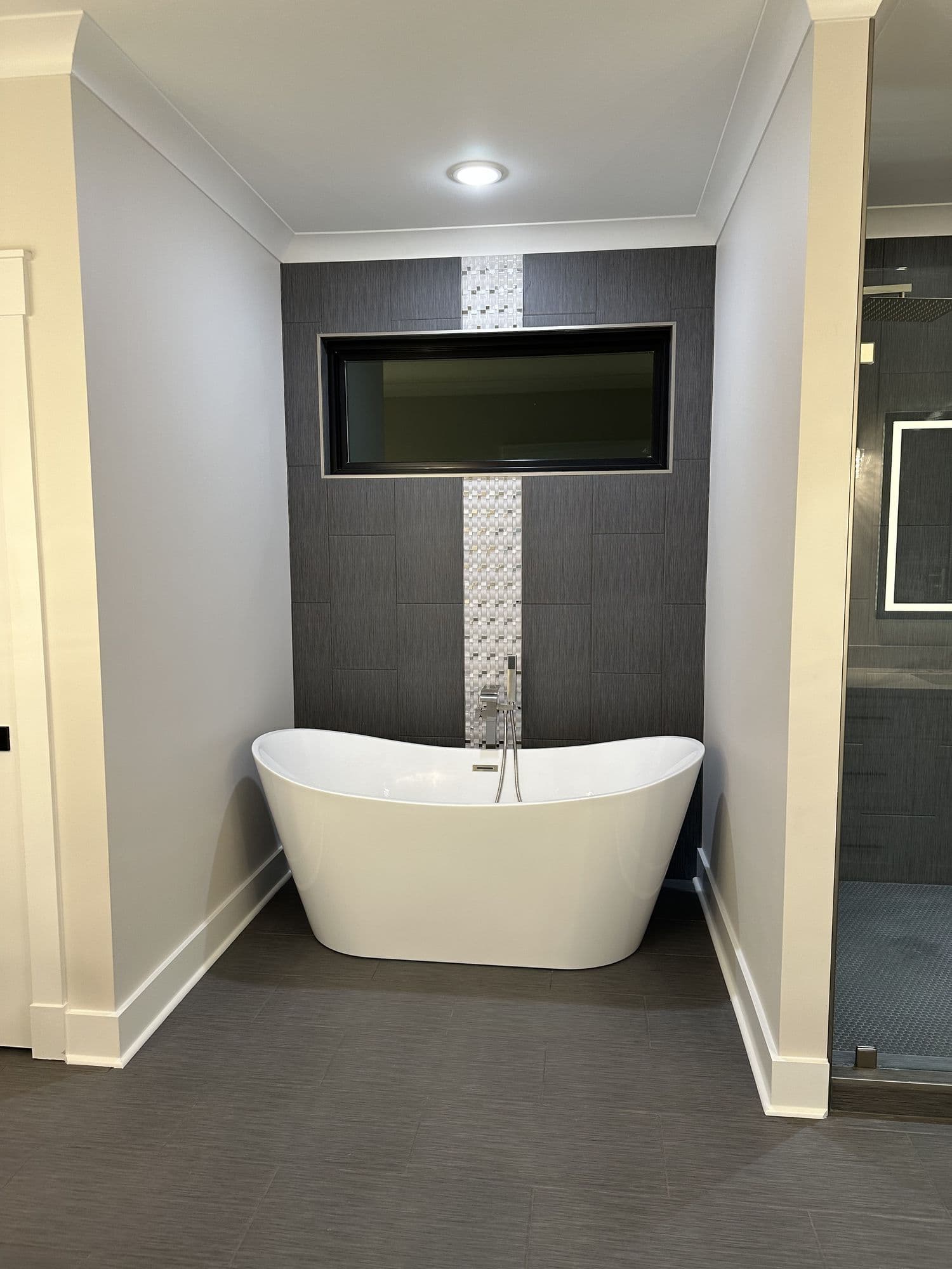 Freestanding soaking tub against a tiled feature wall
