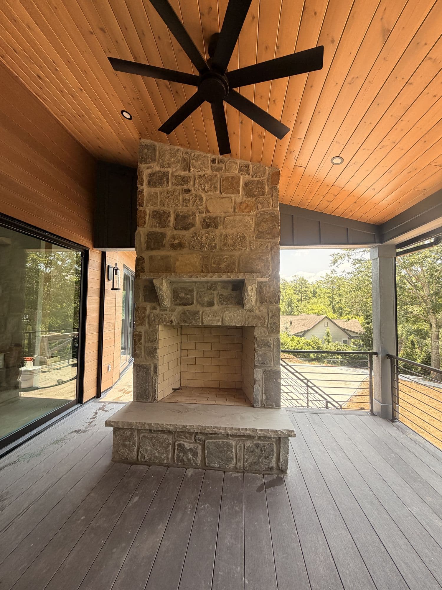 Covered porch with cedar ceiling and a stone fireplace